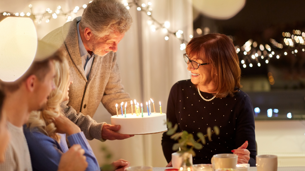 Family celebrating a birthday holding a cake with candles.
